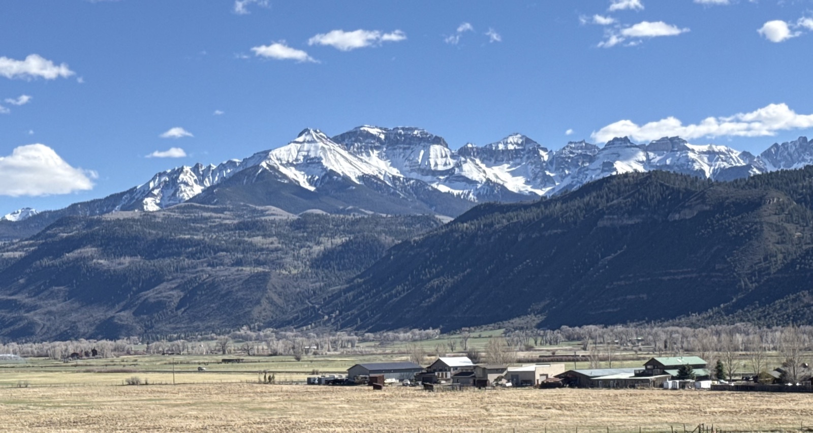 Snowcapped Colorado mountains rising above a ranch valley